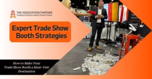 An engaging trade show booth with the text 'Expert Trade Show Booth Strategies' prominently displayed. The Association Partner logo is at the top left corner, signifying advanced tactics for booth design and visitor engagement. A man in a suit interacts with an attendee, demonstrating a lively and dynamic booth setup with money scattered on the floor, suggesting successful business transactions or a marketing activity